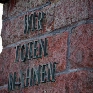 Inschrift "Wir Toten mahnen" auf einer Steinwand