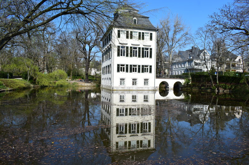 Kleines Wasserschloss umgeben von Bäumen im Frühling